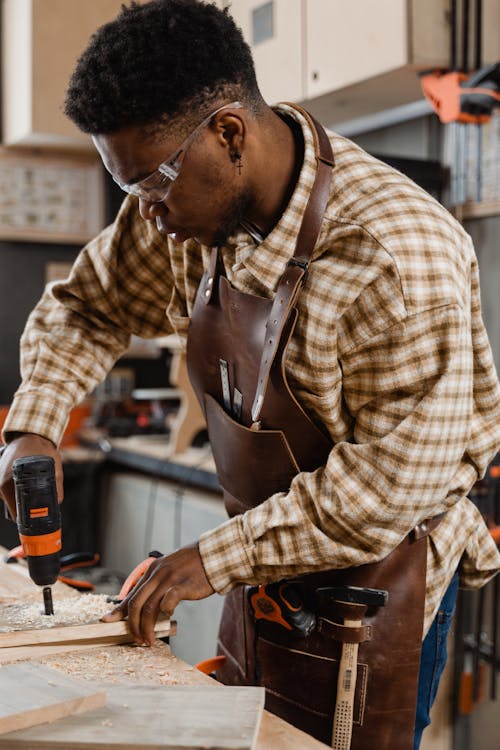 Free Man in Plaid Shirt Drilling a Wood Stock Photo