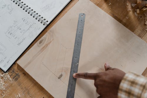 Person Holding Gray Ruler on the Wooden Board