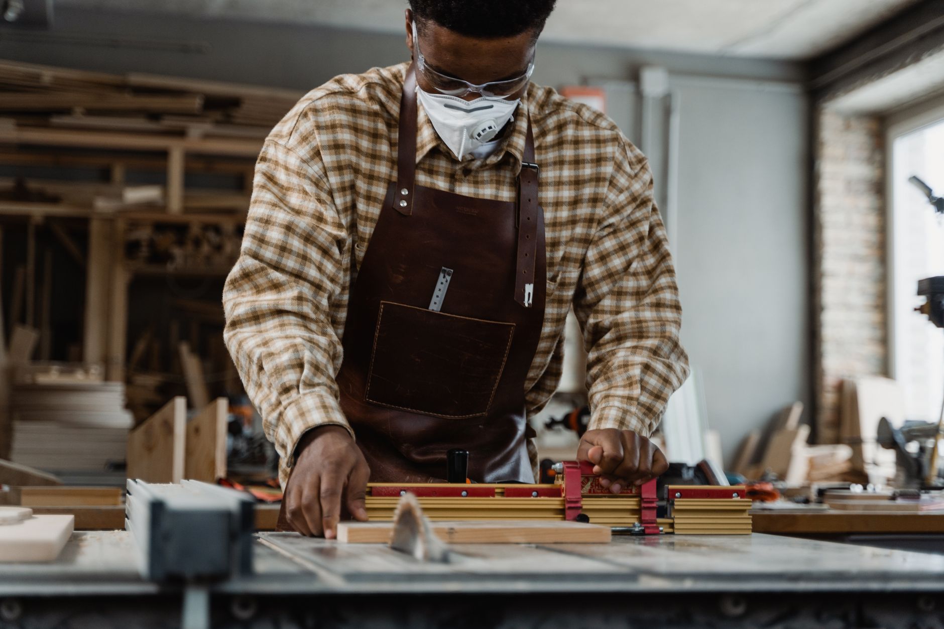 Portrait of a craftsman focused on precise woodcutting using tools in a workshop.
