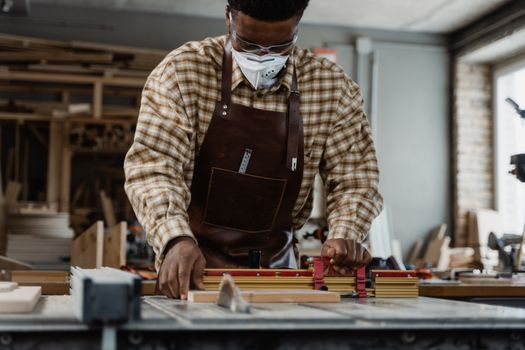 Portrait of a craftsman focused on precise woodcutting using tools in a workshop.