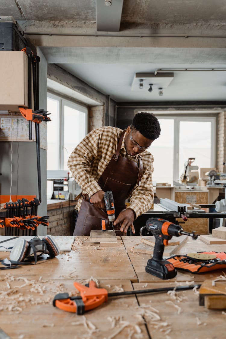 Man Wearing Safety Glasses Drilling A Wood