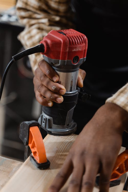 A Person Using a Compact Router on Wood