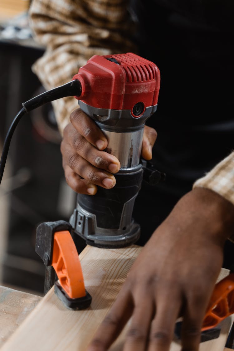 A Person Using A Compact Router On Wood