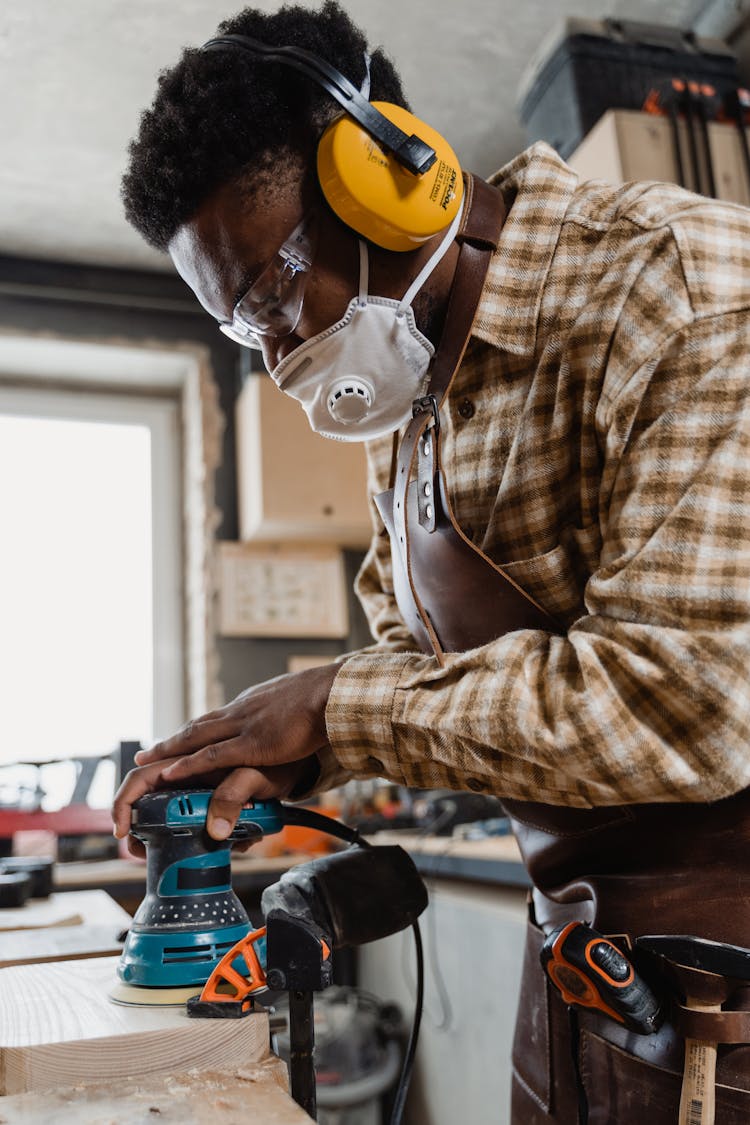 Man Sanding A Piece Of Wood