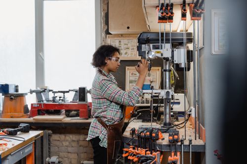 Free An artisan working with precision on a drill machine in a woodworking shop. Stock Photo