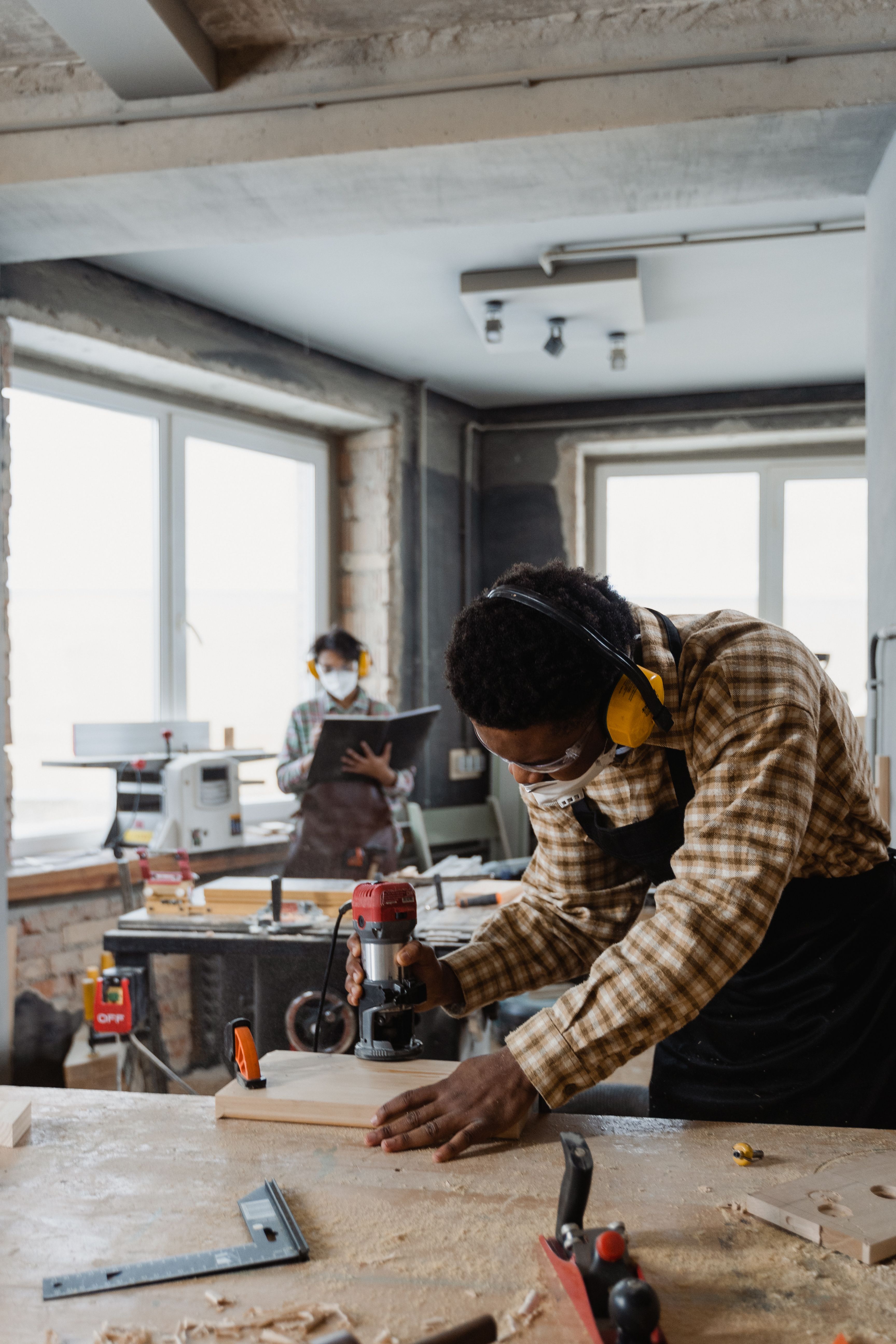 Carpenter wearing safety glasses and hearing protection while operating a power tool on wood