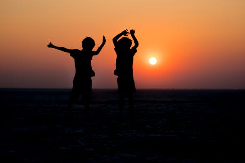 Free Silhouette of Kids Under the Golden Sunset Stock Photo