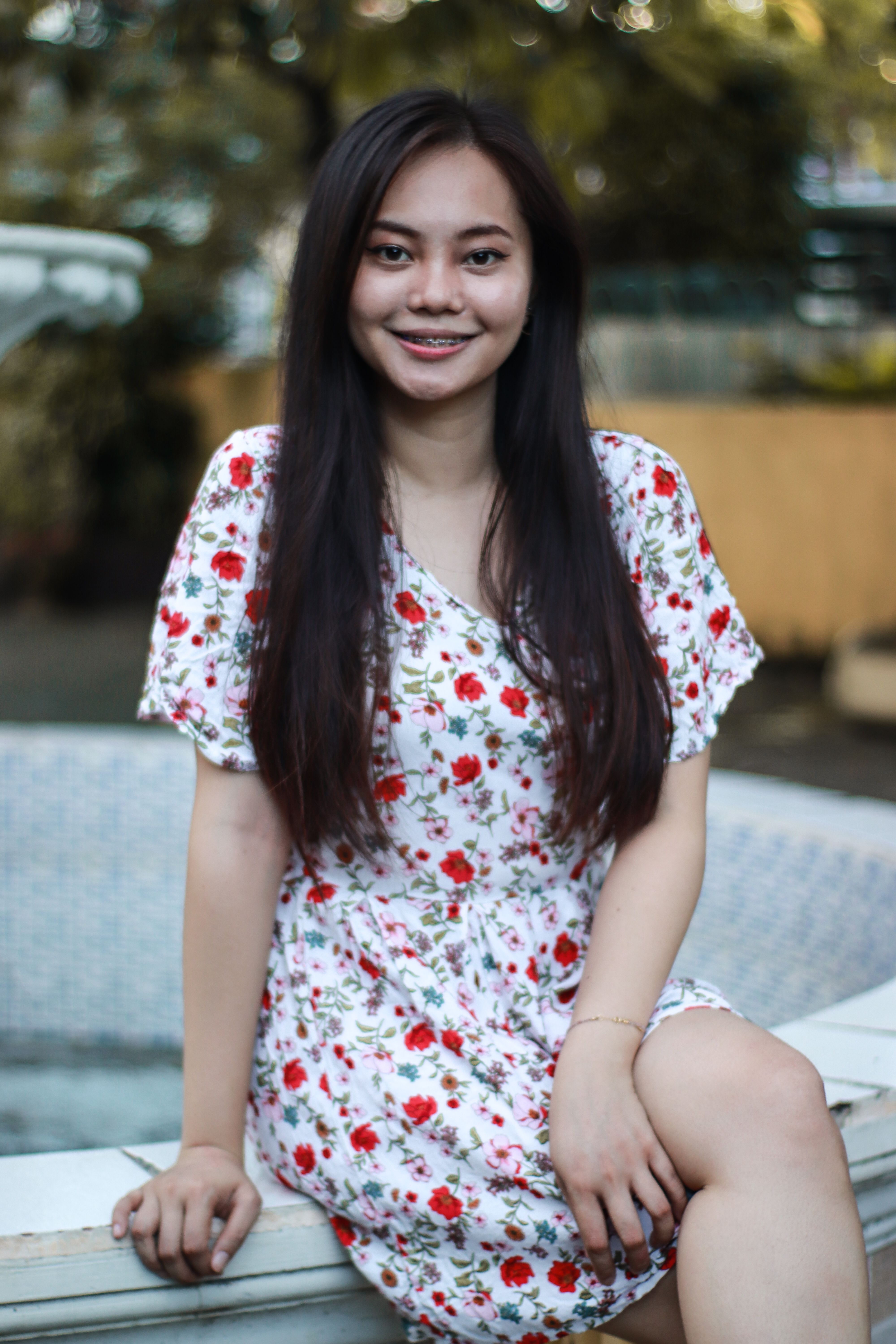 Happy woman in floral dress enjoys sunny day outdoors, showcasing vibrant summer fashion.