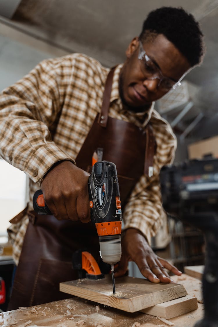 A Man Drilling Into A Wood Board