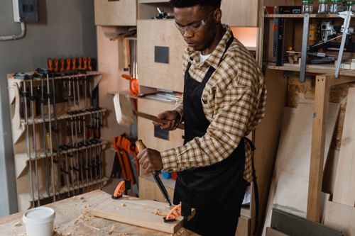 Free A skilled woodworker carving wood in a workshop environment, surrounded by tools and materials. Stock Photo