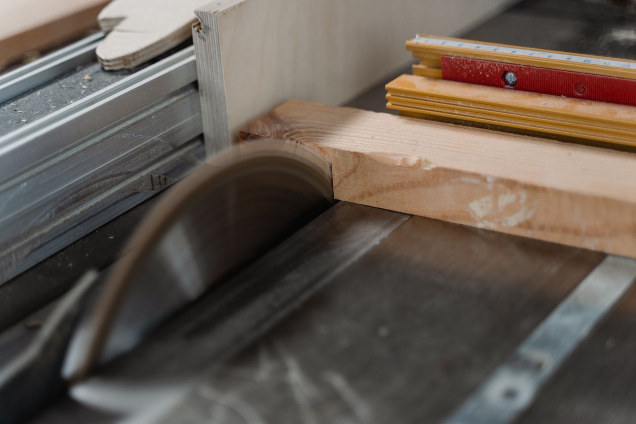 Carpenter guiding a plank through a table saw