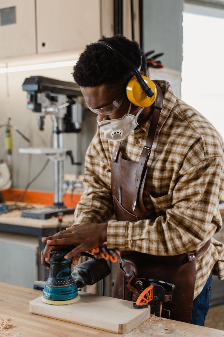 Photo Of A Man Using A Sander On A Piece Of Wood