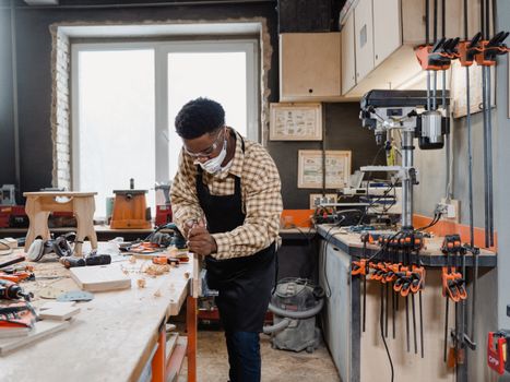 A dedicated carpenter wearing a facemask crafting wood in a workshop.