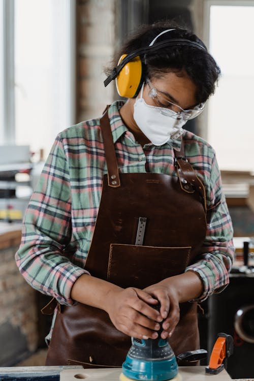 Photo of a Woman with a Leather Apron Using a Sander
