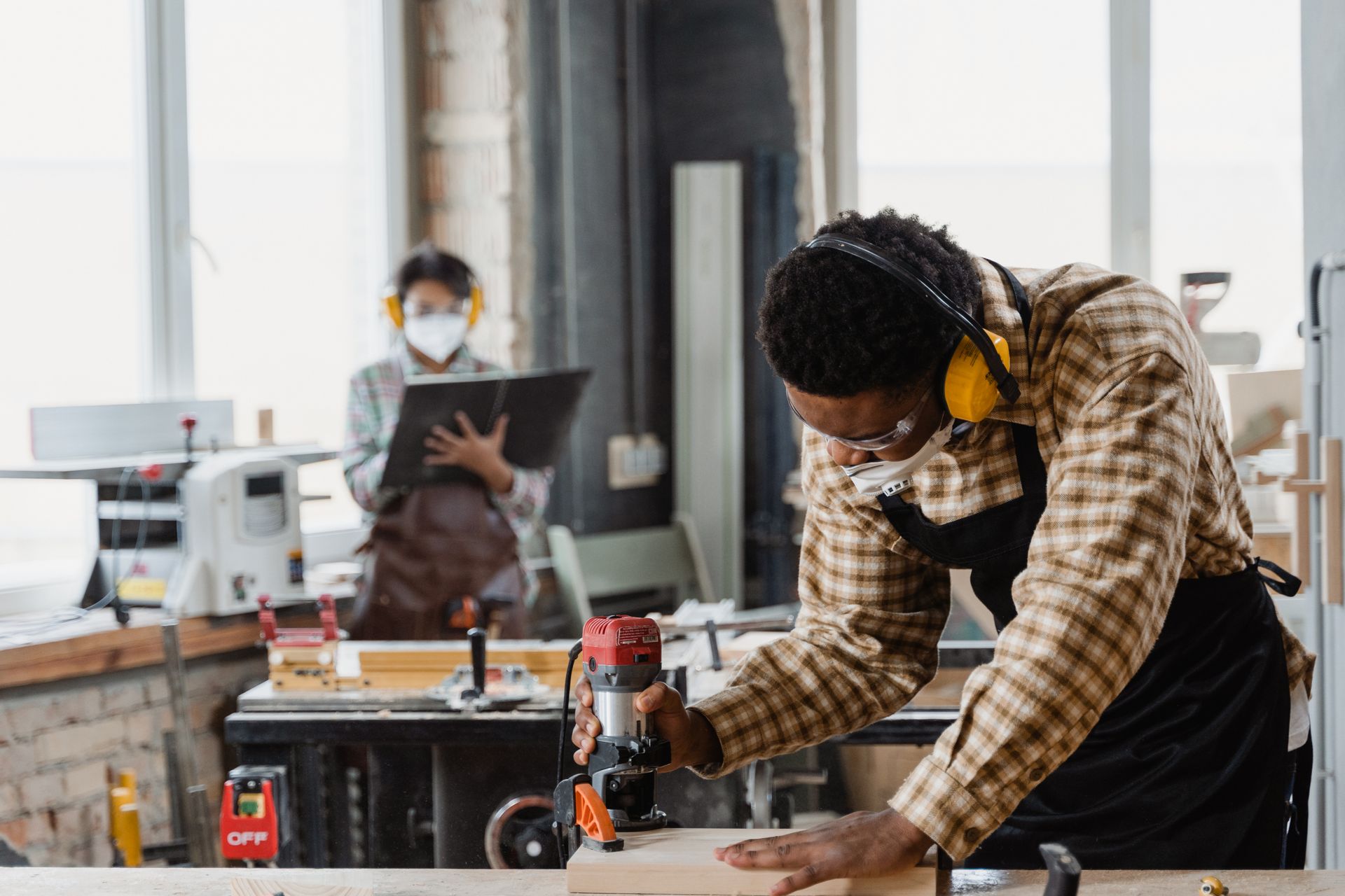 Two artisans planing and sanding wood together at a workbench