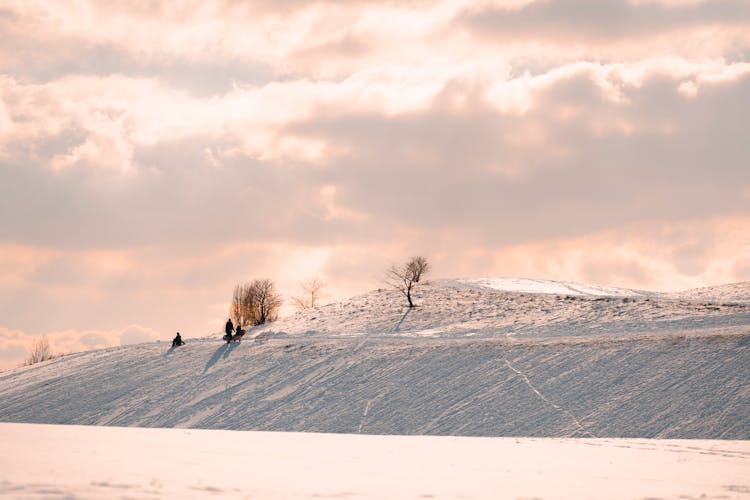 Anonymous People With Sledge Walking On Snowy Hill Slope