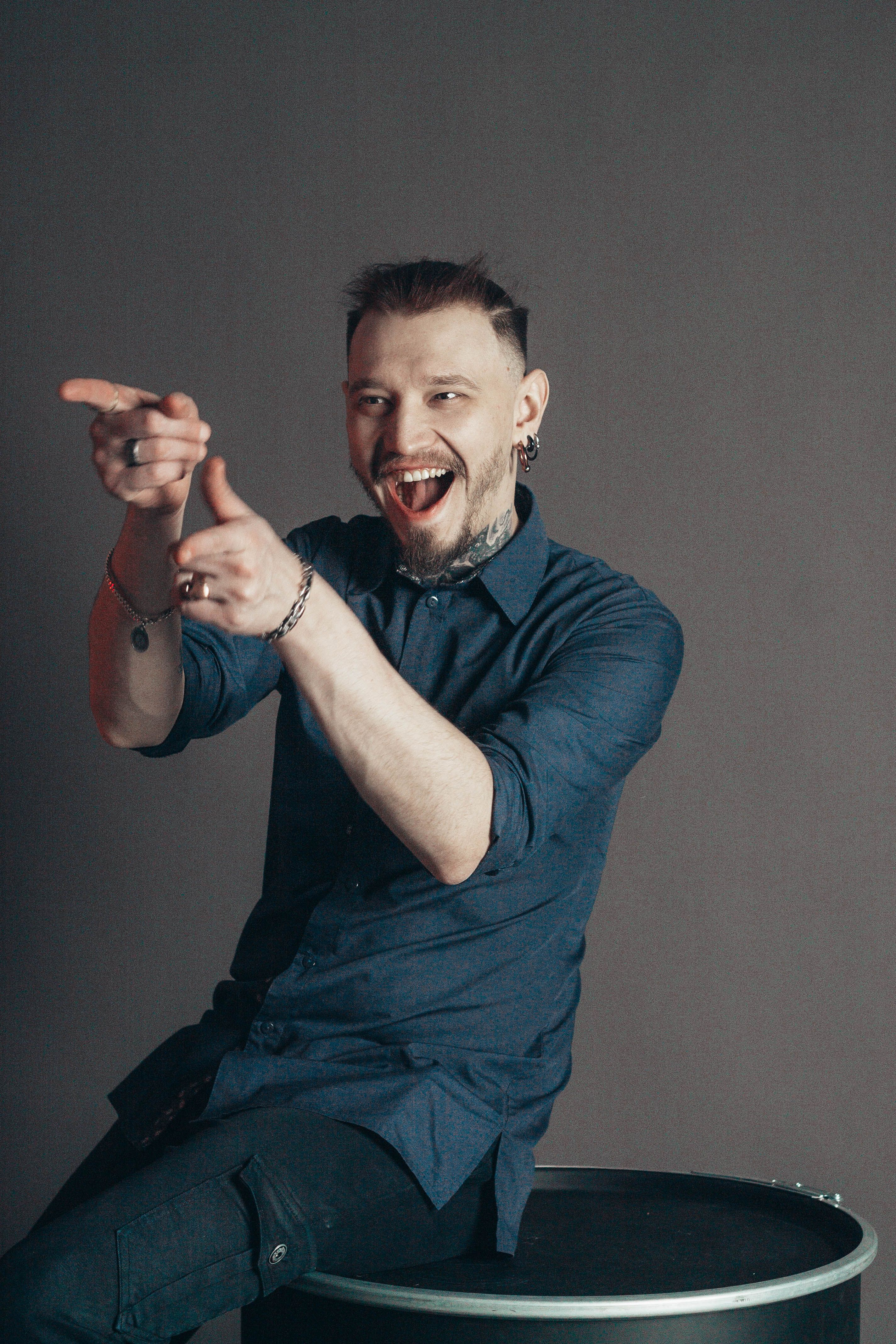 Cheerful man pointing and smiling in a studio portrait setting.