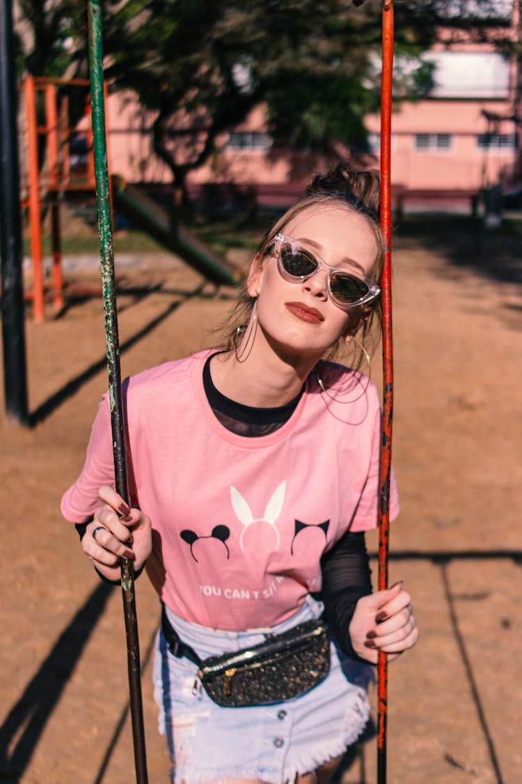 Young Woman On A Playground Sitting On The Swing 