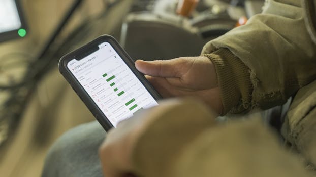 Close-up of a person in winter clothing analyzing farming data on a smartphone screen.