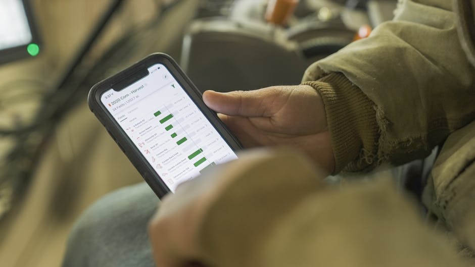 Close-up of a person in winter clothing analyzing farming data on a smartphone screen.
