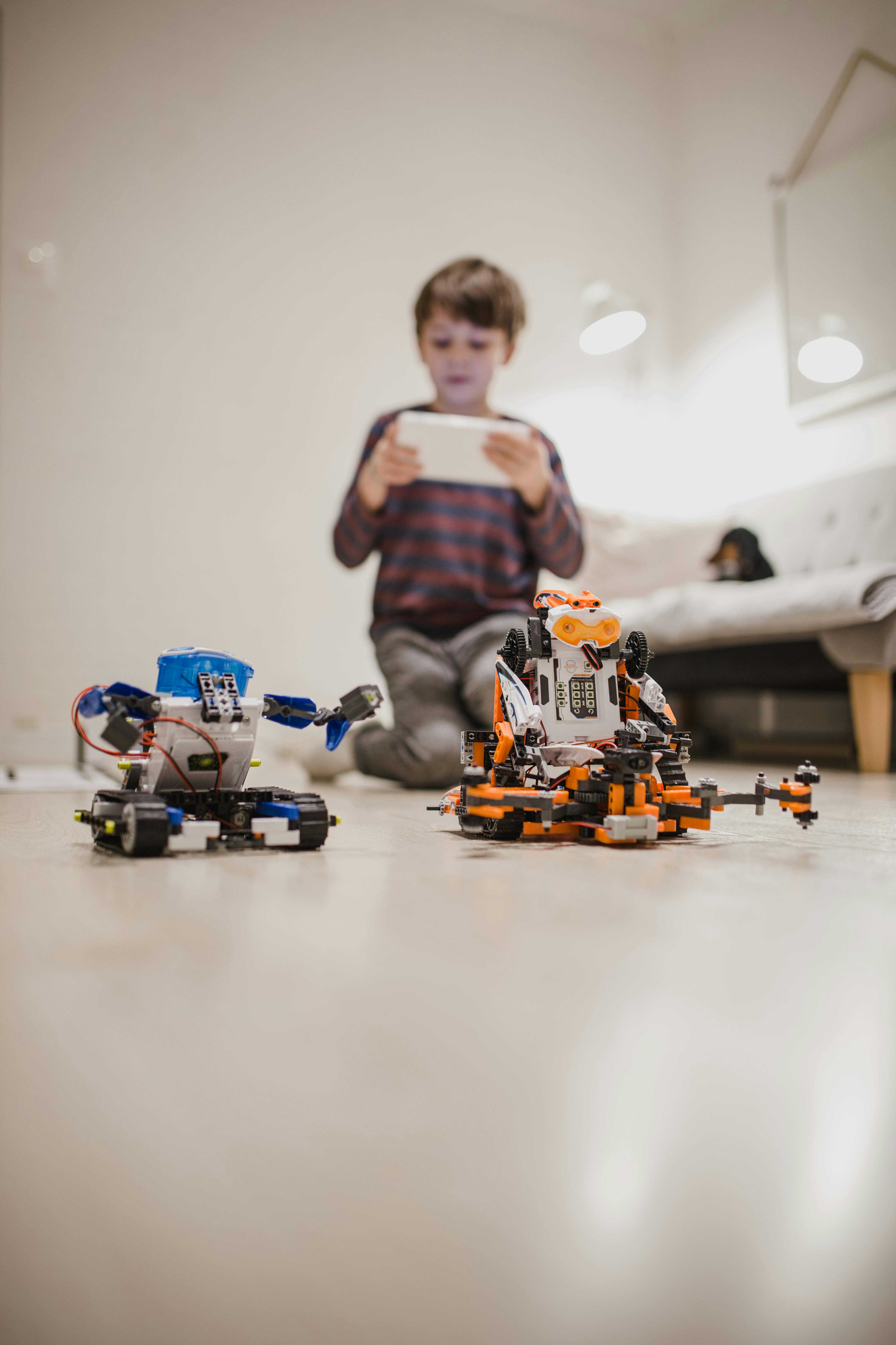 cute boy using tablet on floor with robots