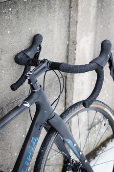 Detailed view of a racing bike leaning against a concrete wall on a snowy day.