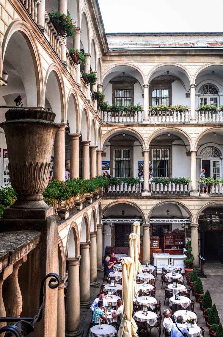 Old Stone Building Facade Against Unrecognizable People In Street Cafe