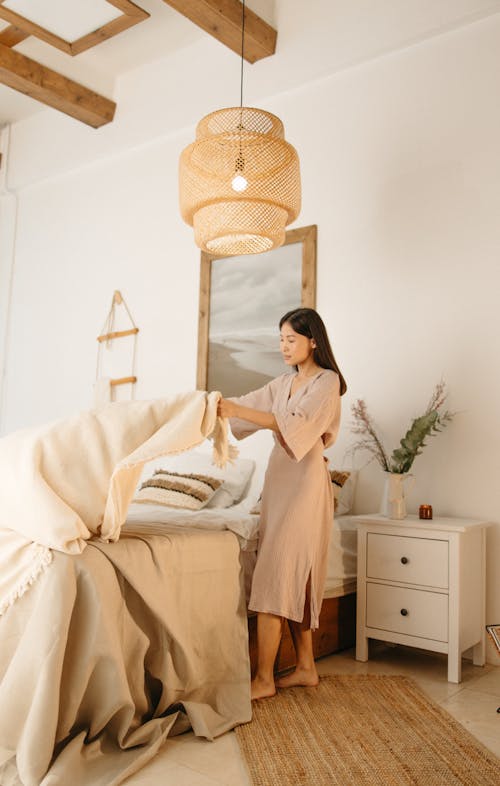 Free Woman in Brown Dress Fixing the Bed Linen Stock Photo