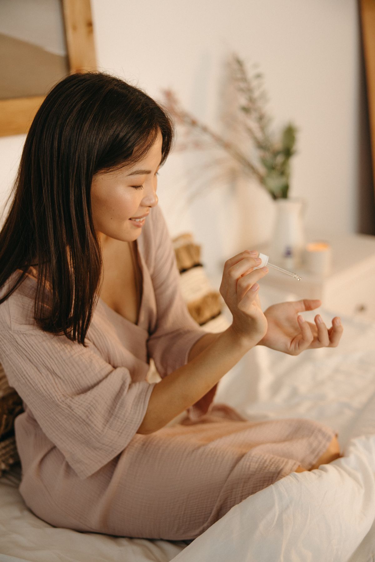 Woman applying nightly retinol serum in a cozy bedroom self-care setting