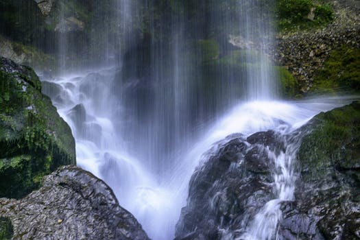Long exposure of a beautiful waterfall in Sainte-Engrace, France showcasing lush greenery and mossy rocks.
