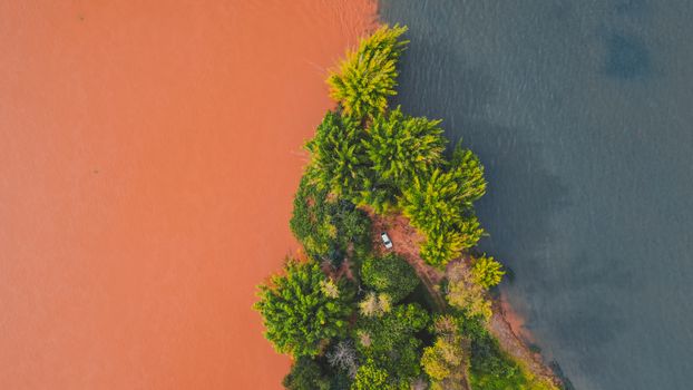 Scenic meeting of waters of two colored rivers near lush green trees