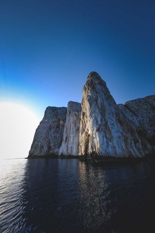 Free High steep stony coast washed by clear water of rippling sea under clear blue sky Stock Photo