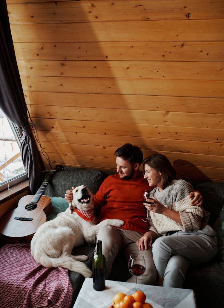 Happy Couple With Dog Cuddling In Cottage