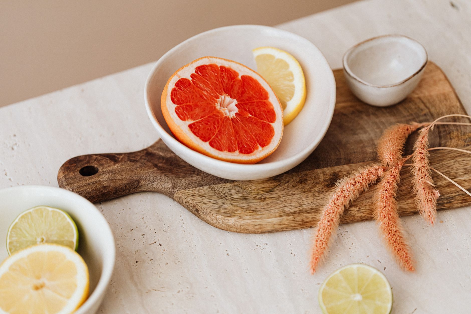 Bright citrus slices displayed in bowls on a wooden board, offering a fresh, minimalist aesthetic.
