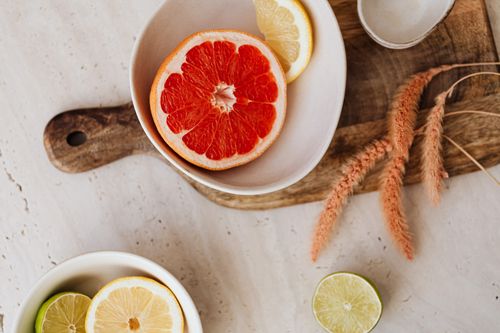 Free Overhead view of a grapefruit, lemon, and lime arrangement in bowls on a rustic wooden chopping board. Stock Photo