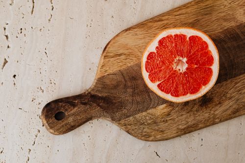 Free Top view of a vibrant grapefruit slice on a rustic wooden cutting board. Stock Photo
