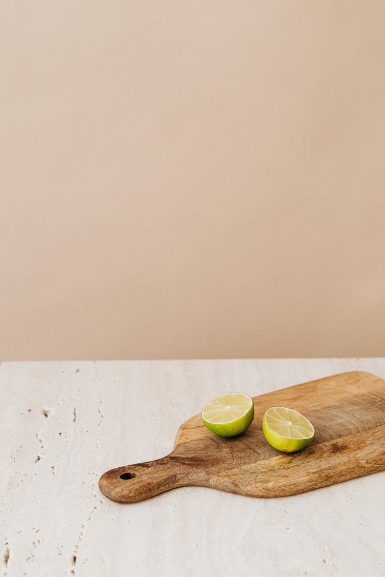 Lime Cut In Halves Lying On Cutting Board