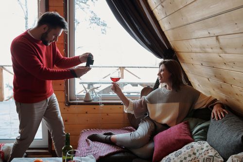 Free A cozy moment indoors with a couple enjoying wine and photography. Stock Photo