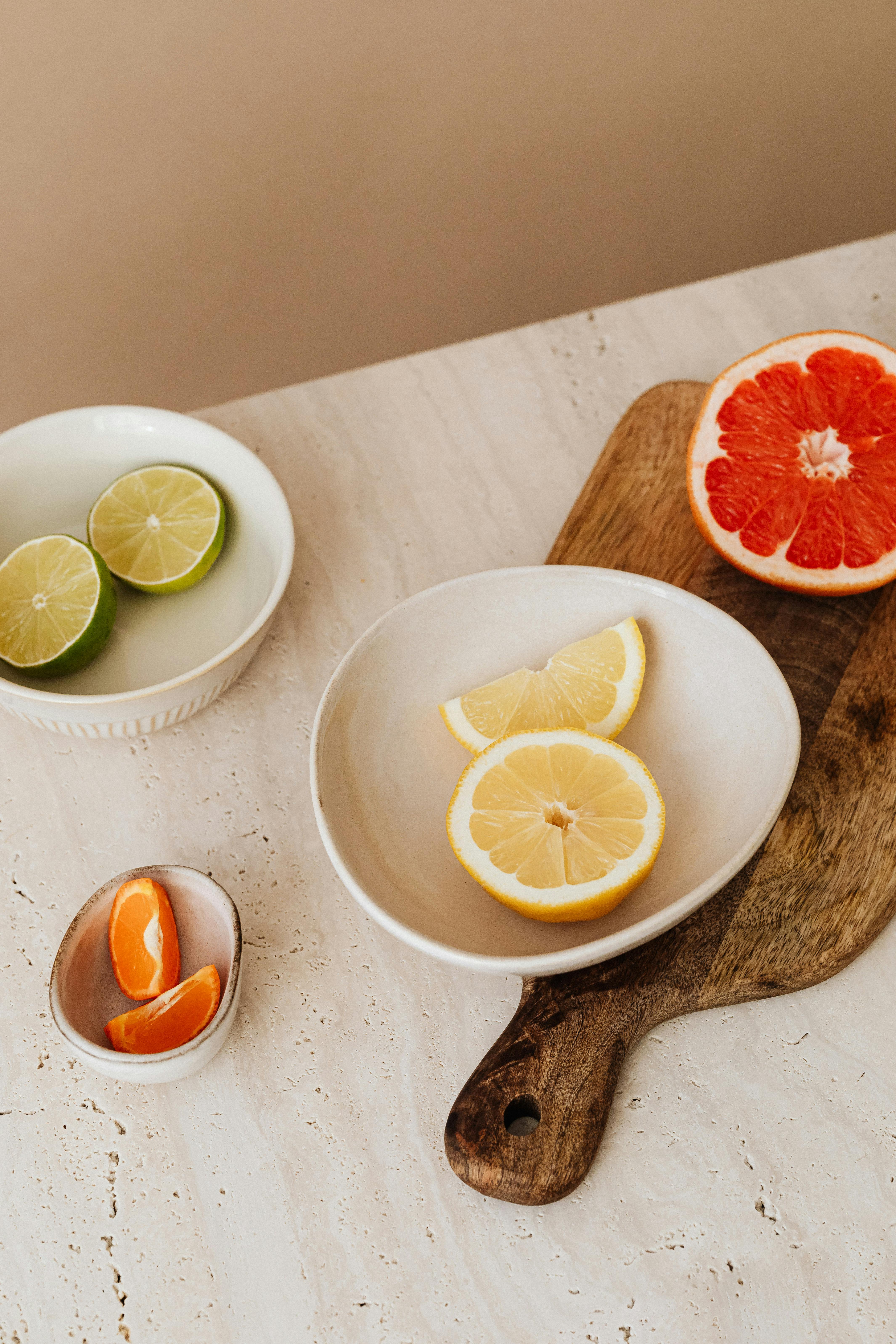 Styled citrus fruits including lemons, limes, and grapefruit on marble and wood surfaces.