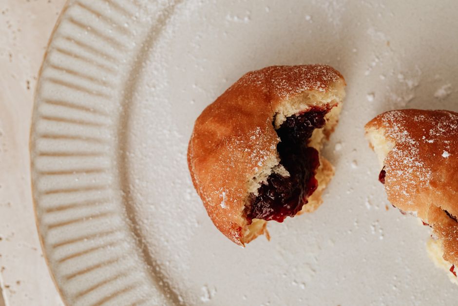 A delicious close-up of a jelly-filled donut on a white plate, sprinkled with powdered sugar.