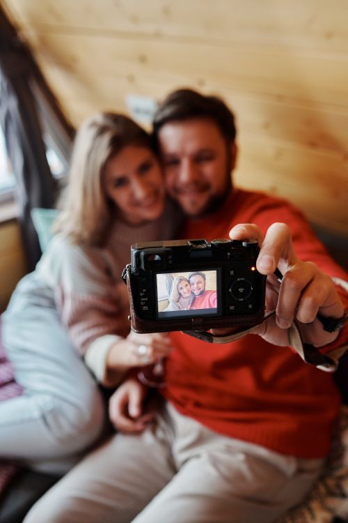 Free Happy couple taking a selfie indoors with a digital camera, capturing a joyful moment. Stock Photo