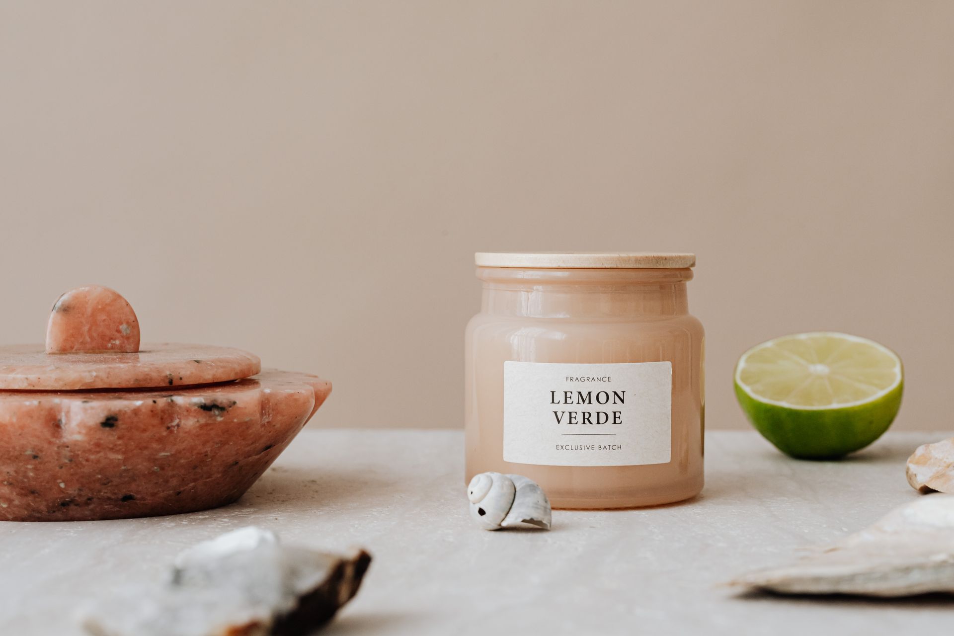 A fragrant candle surrounded by lime and natural stones on a neutral background.