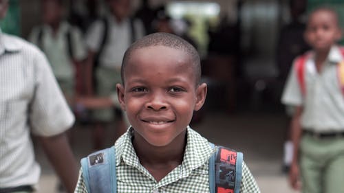 Boy In Plaid Button Up Shirt Smiling With Backpack