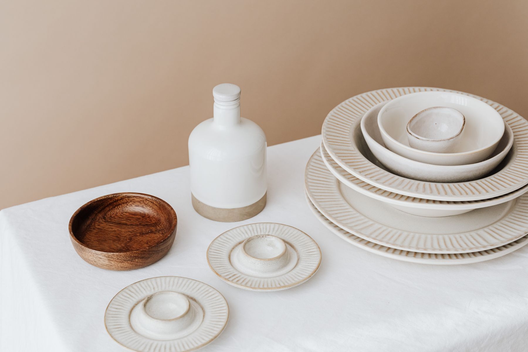 Neutral ceramic plates and bowls arranged on a light dining table