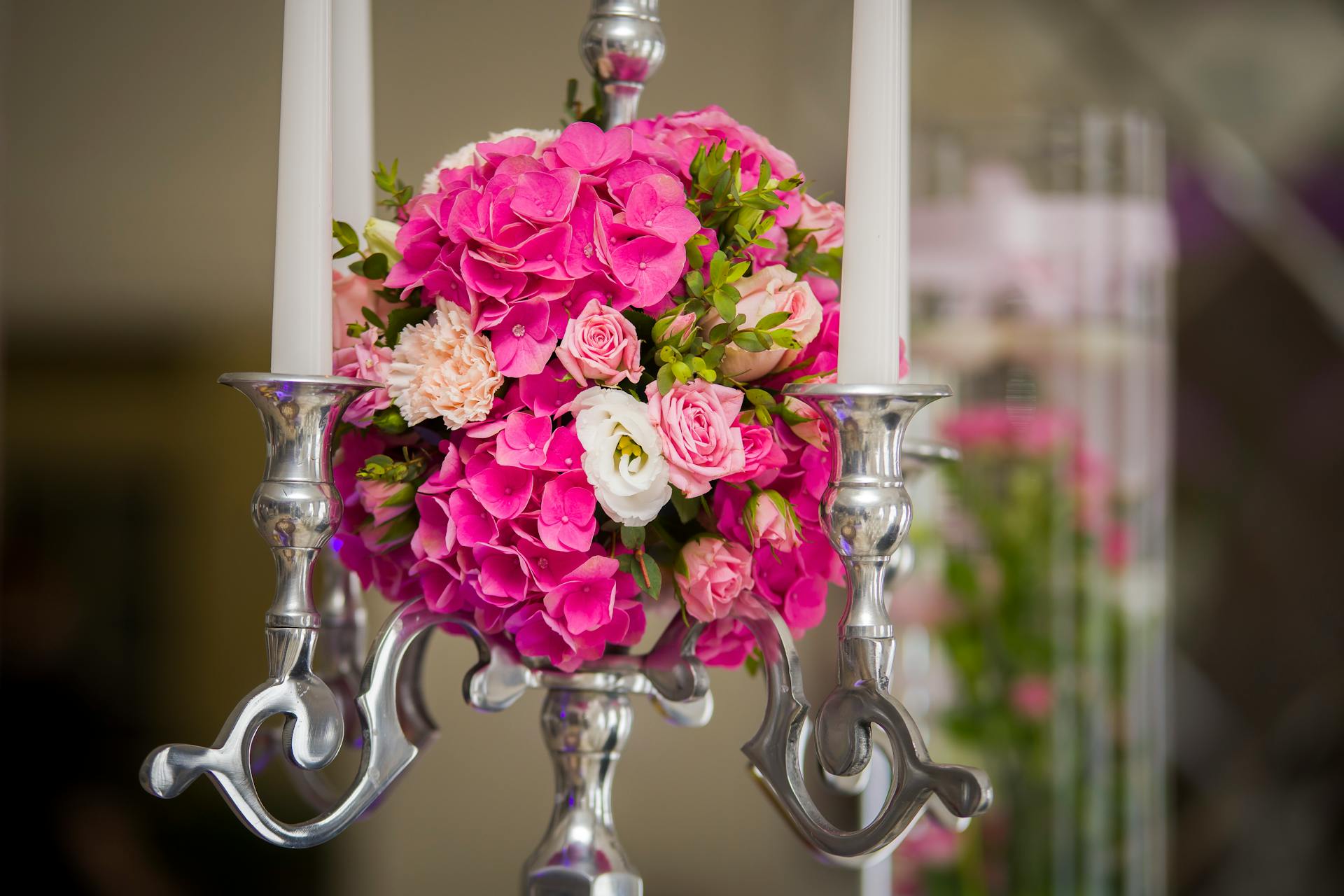 Stylish candlestick decorated by festive bouquet with pink Hydrangea flowers and roses against blurred background