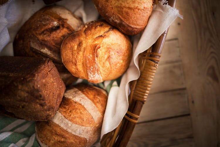 Fresh Bread In Basket Placed On Wooden Surface