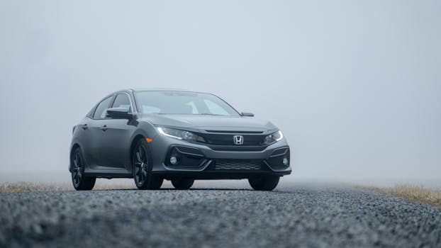 A sleek silver car parked on a foggy road, showcasing its elegance.