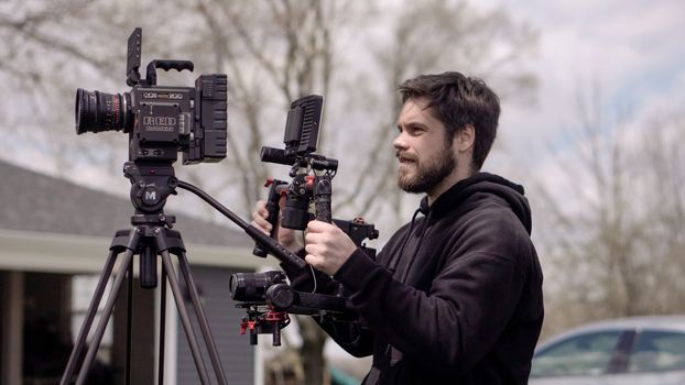 Cameraman operating professional video camera setup outdoors in a casual setting.