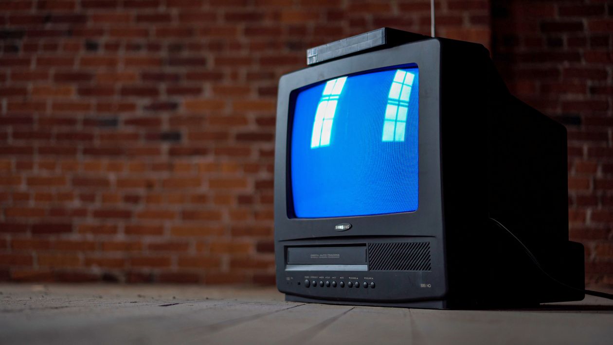 Vieille télévision cathodique avec écran bleu et cassette VHS.