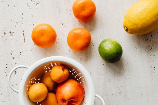 A variety of fresh fruits including apricots, oranges, lemon, and lime arranged artfully.